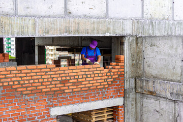 Construction of a brick wall in a monolithic frame building, a bricklayer lays out a partition...
