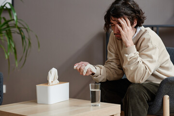 Obraz premium Horizontal medium portrait of young Caucasian man suffering depression having psychologist appointment sitting with eyes closed and crying