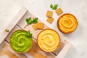 Flatlay of different types of colorful hummus in bowls. Vegan food background