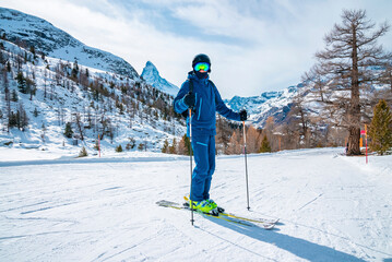 Skier skiing on snow covered landscape. Scenic matterhorn mountain range against sky. Tourist...