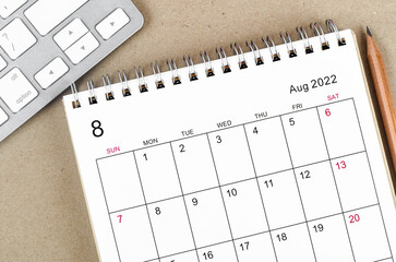 August 2022 desk calendar with pencil on wooden background.