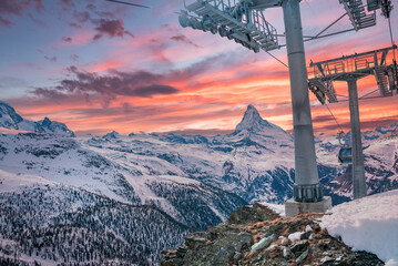 Cable cars moving by snowcapped matterhorn. Aerial tramcar against cloudy sky during sunset. Scenic...