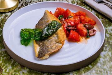 Dorado on grill with vegetables on a grey plate