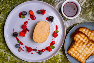 terrine de foie gras on grey plate with berries top view