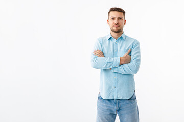 Portrait of a cheerful young man in a blue shirt on a white background. The guy stands, looks at the camera and smiles.
