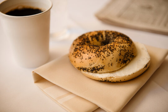 poppyseed bagel with coffee and news paper