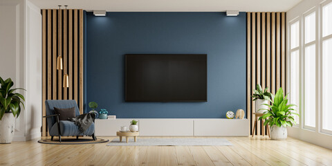 TV and Cabinet in modern living room with blue armchair on dark blue concrete wall background.