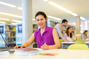 Portrait of positive asian woman with laptop in public library