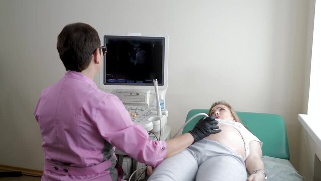 The doctor uses ultrasound equipment when examining a pregnant woman. A professional female obstetrician-gynecologist conducts a prenatal examination of the expectant mother in a hospital