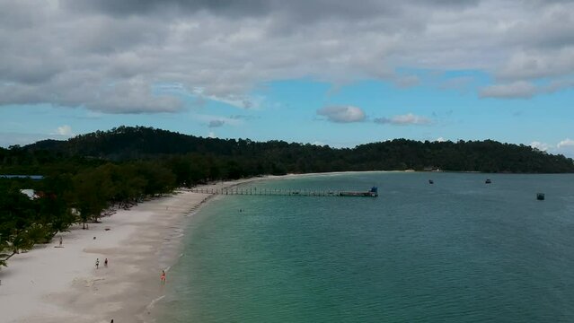 White sandy beach surrounded by jungle. Popular tourist spor in Cambodia, 4K Beach Port, Koh Rong island - aerial crane