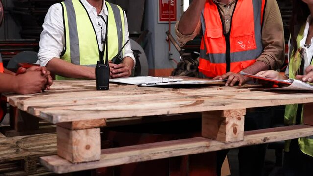 Four heavy industrial engineers stand together in a steel factory. Design discussions, seminars in industrial plants. Engineer teach and write on clipboard to use radio processing machines.