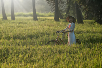 girl with bicycle in fileds. beautiful woman with Vietnam culture traditional dress, Ao dai and riding bicycle