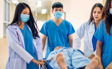 Group of professional medical doctor team and assistant with stethoscope in uniform taking seriously injured coma patient to operation emergency theatre room in hospital.health medical care concept