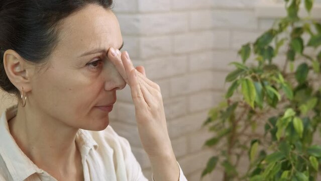 Woman postural massage on nose. A healthy woman practice postural massage on her nose for breathing in the room.
