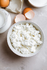 Cottage cheese in a ceramic bowl, jug of milk, flour and eggs. Ingredients for cooking. Top view 