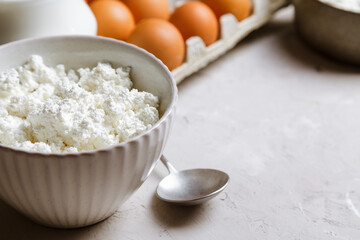 Cottage cheese in a ceramic bowl, jug of milk and eggs. Ingredients for cooking