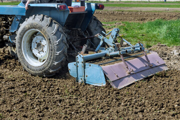 Tractor crushing and loosening soil before seedling.