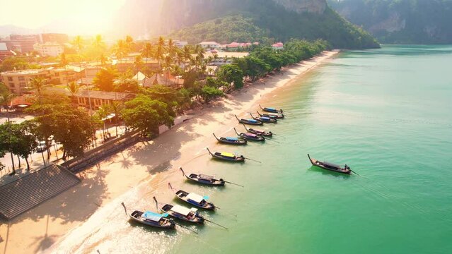 Aerial top view over city and sandy beach with turquoise water, passenger boats on shore. beautiful beach in the Andaman Sea (Aonang, Krabi, Thailand). 4K drone footage. Nature and travel concept
