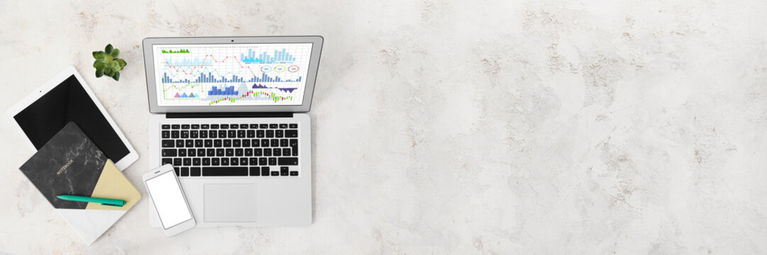 Business statistics on screen of modern laptop, mobile phone, tablet computer and office stationery on grunge background with space for text