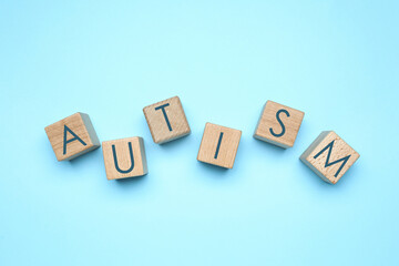 Word AUTISM made of cubes on light blue background