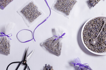 DIY lavender sachets for home, ideas for gifts, transparent package with natural scented dried flowers, white lavender colored silk cloth on table. Aromatherapy and herbal medicine concept