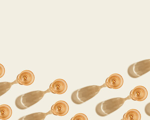 Glasses of white wine from pale pink colored glass with dark shadows from sunlight, creative summer drink minimal concept, modern glass on beige color background, copy space