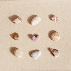 Aesthetic minimal pattern with set of pebble stones on fine sand background. Square composition...