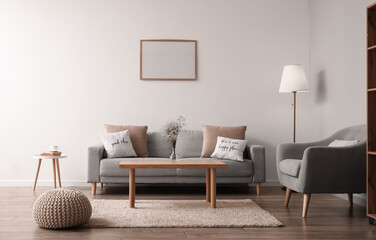 Interior of modern living room with comfortable furniture and blank photo frame on light wall
