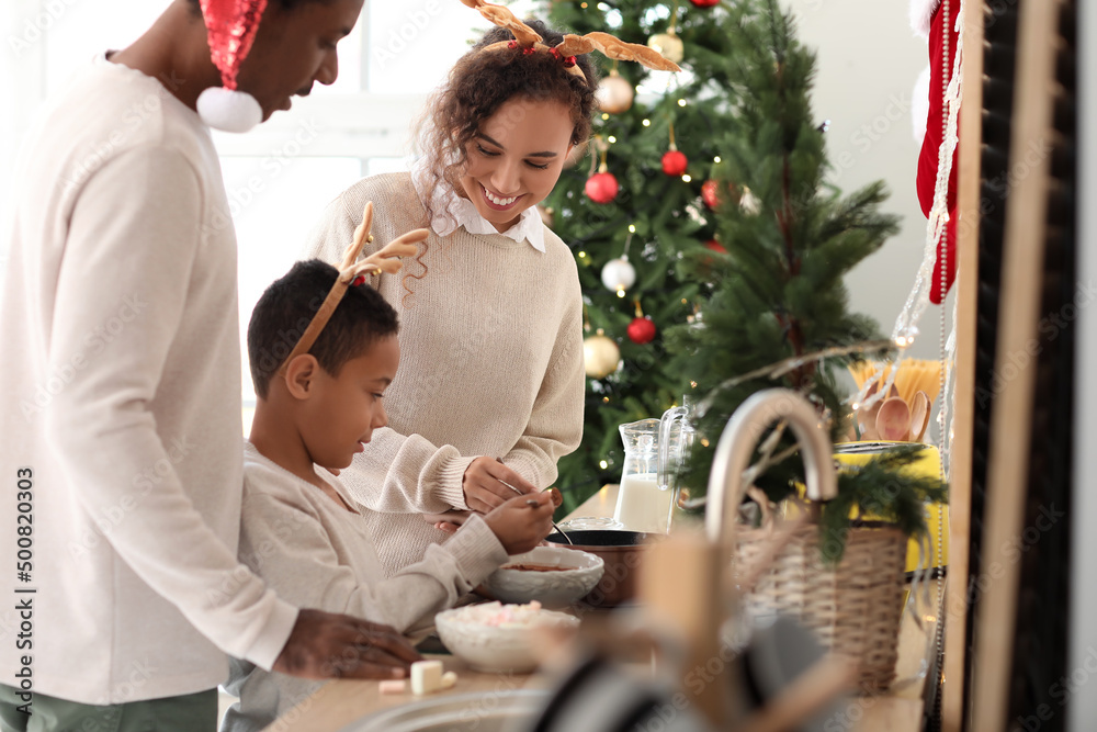 Poster African-American family preparing tasty hot chocolate in kitchen on Christmas eve