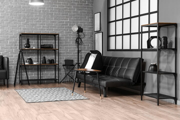 Interior of modern photo studio with shelving units, couch and professional equipment