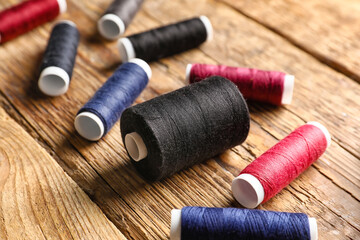 Sewing threads on wooden background, closeup