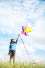 Woman holding balloons running on green meadow white cloud and blue sky with happiness Cheerful and relax. Hands holding vibrant air balloons play on birthday party happy times summer sunlight outdoor