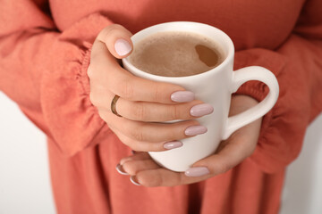Woman with stylish manicure and jewelry holding cup of coffee, closeup