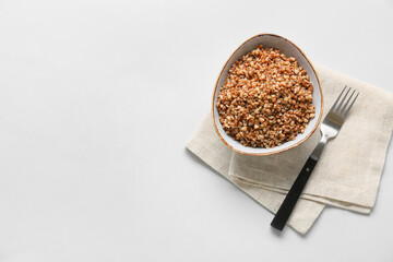 Bowl of tasty buckwheat porridge on white background, top view