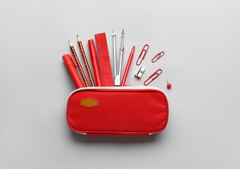 Pencil case with school stationery on light background
