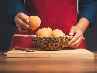 Chef hand holding a ripe peach while standing in the kitchen