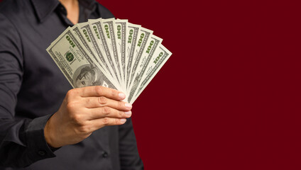 Businessman holding US banknotes on a red background while standing in the studio