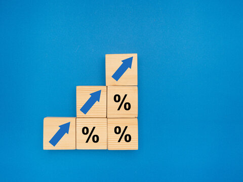 Finance and interest rate concept. Wooden cubes with arrows up and percentage symbol over a blue background