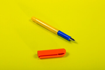 Yellow fountain pen with orange cap on yellow background