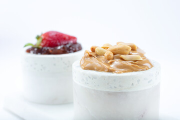 A view cups of peanut butter and strawberry jelly.