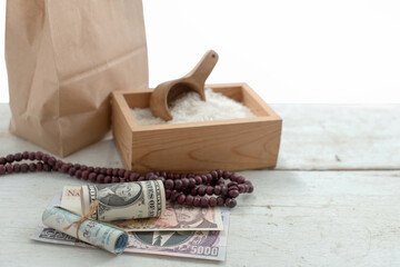Fototapeta na wymiar Banknote, rosary, brown paper bag and rice in the wooden box, ZAKAT donation for Muslims according to religious principles during the Ramadan month