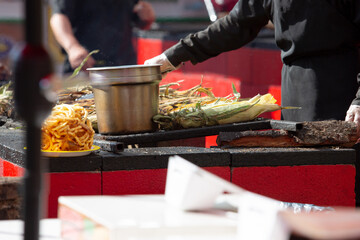 A view of a pit master preparing corn on a grill.