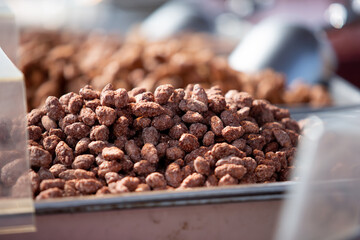 A view of several trays of roasted assorted nuts, on display at a food vendor.