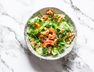 Creative Caesar salad with grilled shrimp on a light marble background, top view