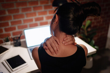 Young working women are tired from working hard at night. She was doing a neck massage to loosen...