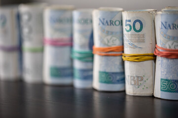 The banknotes rolled and tied together with a rubber band stand on the table top.