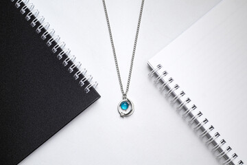 Silver chain necklaces with blue diamond pendant on white office desk