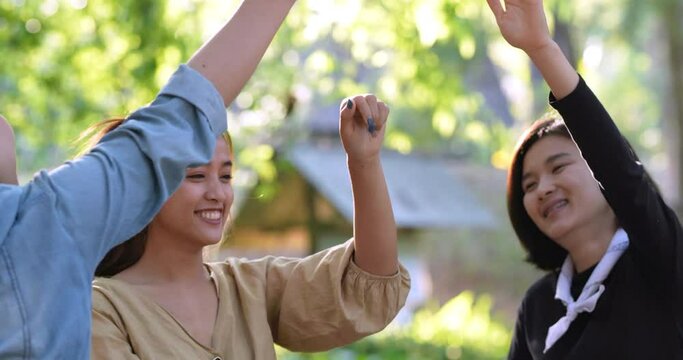 Handheld shot, Group of women giving five to each other on camping with toothy smile and happy together at front of camping tent in forest