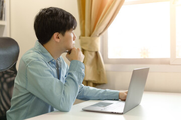 Young adult trader man, businessman investor thinking studying, learning online course about business investing money, trading on laptop on new stock market or Bitcoin Cryptocurrency online platform.