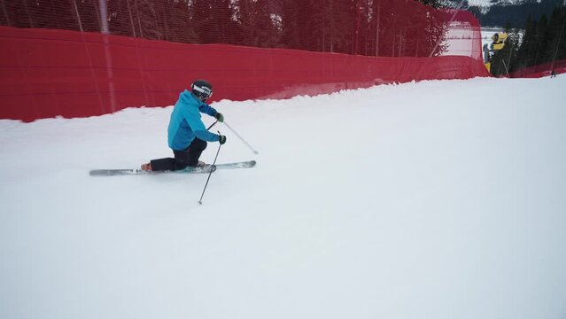 4K of skilled telemark skier with a blue jacket going fast downhill with small curves on a cold winter day in Norway